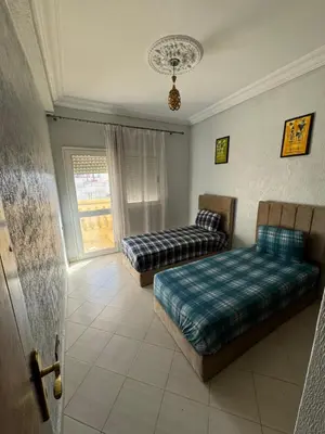 a living room with two beds and a window at Appartement 3 chambre et deux salon pour les familles in Fès