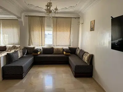 a living room with a couch and two windows at Appartement 3 chambre et deux salon pour les familles in Fès