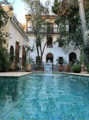 a swimming pool with a fountain in front of a building at Riad Hanael Garden & Spa in Fès