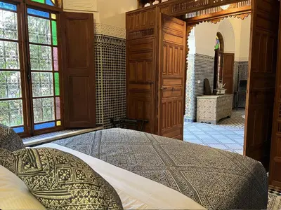 a bedroom with a large bed and a bathroom at Riad Hanael Garden & Spa in Fès