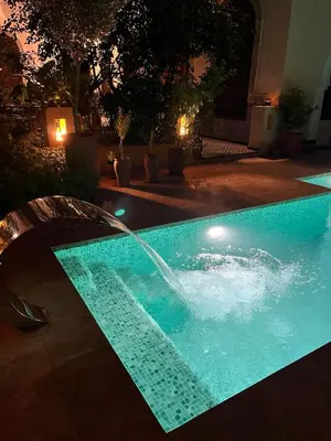 a swimming pool with a fountain in a yard at night at Riad Hanael Garden & Spa in Fès