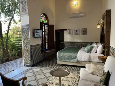 a bedroom with a bed and a living room at Riad Hanael Garden & Spa in Fès