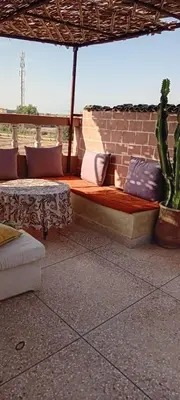 a couch sitting under an umbrella on a patio at Dar Fouzia in Bothmat