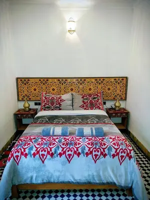 a bedroom with a bed with a red and blue bedspread at Dar Abdellah in Fès