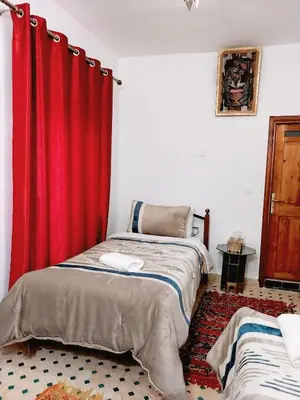 two beds in a room with red curtains at Dar Abdellah in Fès