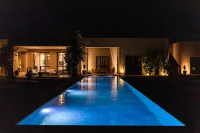 a swimming pool in front of a house at night at Villa A Atlas Retreat Luxury B and B Beni Mellal in Beni Mellal