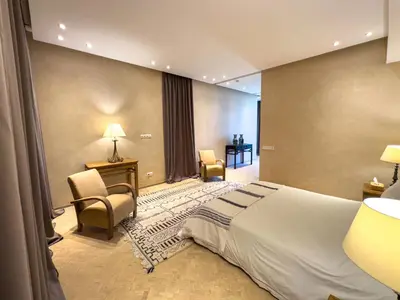 a bedroom with a bed and a desk and chairs at Villa A Atlas Retreat Luxury B and B Beni Mellal in Beni Mellal