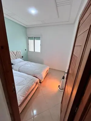 two beds in a room with a door open at Charming Two Bedroom Apartment in Fes Near City Center in Fès