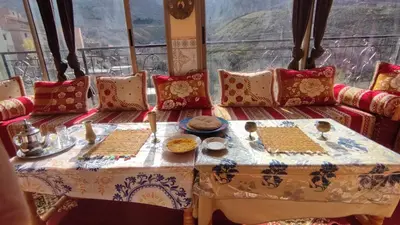a table with plates of food on it in front of a window at Dr ouanskra asni el haouz imlil in Imlil