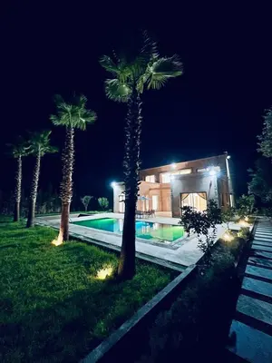 a house with palm trees and a swimming pool at night at Villa MK in Aghmat