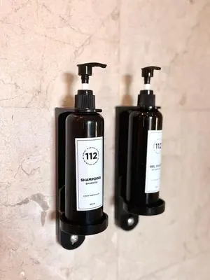 two black bottles of soap sitting on a wall at Appartement Cosy avec grande terrasse et piscine en face du stade Can2025 in Dar Rahal Ben Saïd
