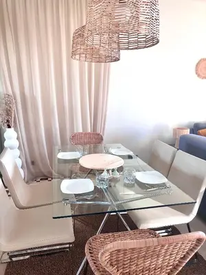 a dining room with a glass table and chairs at Appartement Cosy avec grande terrasse et piscine en face du stade Can2025 in Dar Rahal Ben Saïd
