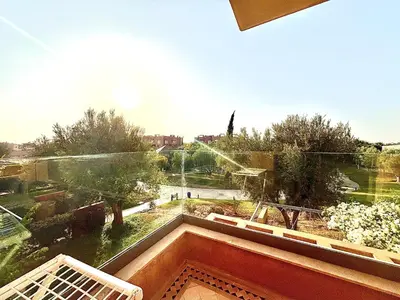 a view of a garden from a window of a building at Appartement Cosy avec grande terrasse et piscine en face du stade Can2025 in Dar Rahal Ben Saïd