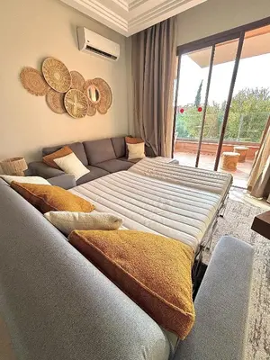 a living room with two beds and a couch at Appartement Cosy avec grande terrasse et piscine en face du stade Can2025 in Dar Rahal Ben Saïd