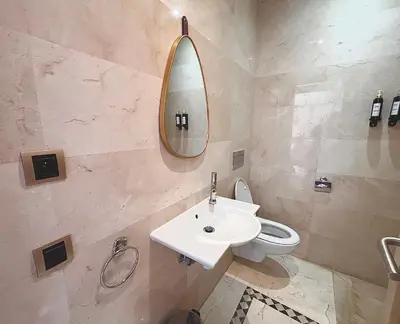 a bathroom with a sink and a toilet and a mirror at Appartement Cosy avec grande terrasse et piscine en face du stade Can2025 in Dar Rahal Ben Saïd