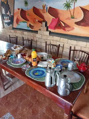 a wooden table with plates of food on it at Gite take your time takojt merzouga in Hassilabied