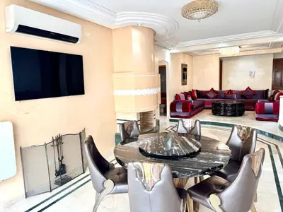 a living room with a table and chairs and a couch at Luxueux appartement Assouan centre-ville in Fès