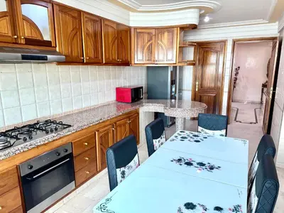 a kitchen with wooden cabinets and a table and chairs at Luxueux appartement Assouan centre-ville in Fès