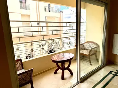 a balcony with a table and chairs and a window at Luxueux appartement Assouan centre-ville in Fès