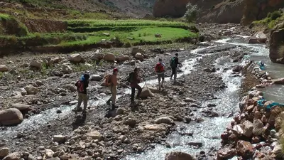 a group of people walking across a river at Auberge Sremt in Sremt