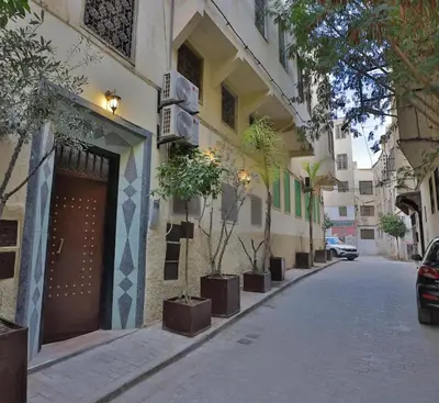 a street with a building with potted trees on it at Dar Chaima Apartment in Fès