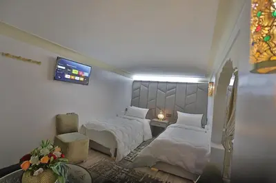 a bedroom with two beds and a tv on the wall at Dar Chaima Apartment in Fès