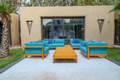 a patio with blue couches and a wooden table at Villa d'exception spa, sport & piscine in Najem
