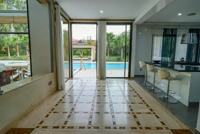 a living room with a tile floor and a pool at Villa d'exception spa, sport & piscine in Najem