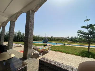 a patio with a view of a swimming pool at la ferme zine in Ain Cheggag