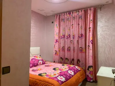 a bedroom with a bed and a pink curtain at la ferme zine in Ain Cheggag