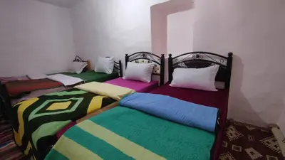 two beds with colorful blankets and pillows in a room at GITE DETAPE DAR AGSWAL DOUAR WANSKRA OUED IMNANE ASNI MARRAKECh in Tacheddirt