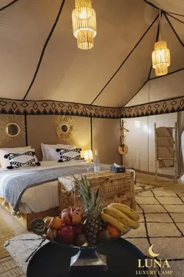 a room with a bed and a table with fruit on it at Luna Luxury Camp Merzouga in Merzouga