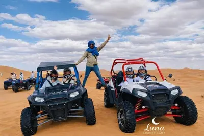 a group of people riding atvs in the desert at Luna Luxury Camp Merzouga in Merzouga