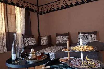 a room with a bed and a table with plates of food at Luna Luxury Camp Merzouga in Merzouga