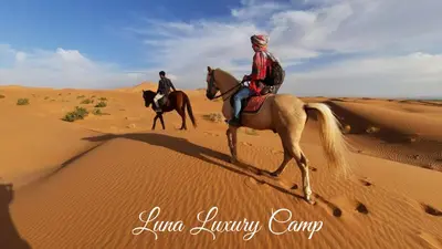 two people riding horses in the desert at Luna Luxury Camp Merzouga in Merzouga
