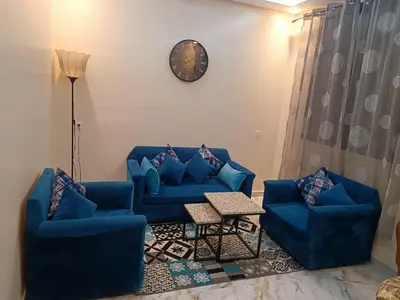 a living room with two blue couches and a clock at Appartement meublé in Meknès