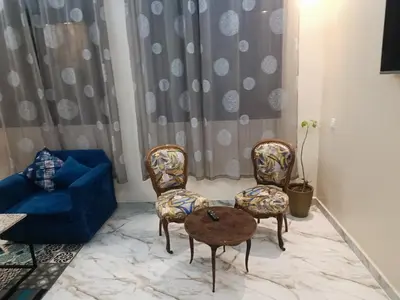 a living room with two chairs and a table at Appartement meublé in Meknès