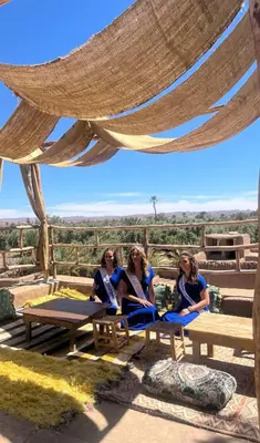 three women sitting on picnic tables under a canopy at Heritage House Skoura in Skoura