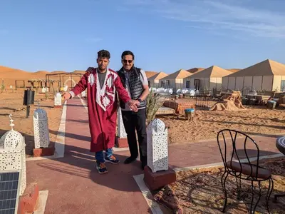 two men standing next to each other in the desert at Safari trips Morocco luxury camp in Merzouga