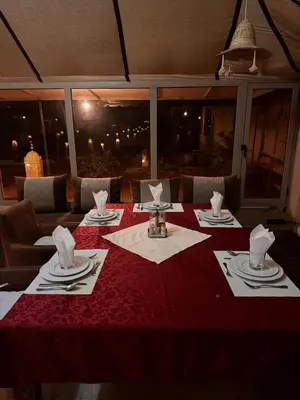 a table with a red table cloth and napkins on it at Safari trips Morocco luxury camp in Merzouga