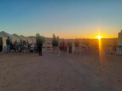 a group of people standing in the desert watching the sunset at Safari trips Morocco luxury camp in Merzouga