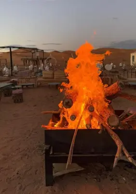 a large fire in the middle of a beach at Safari trips Morocco luxury camp in Merzouga