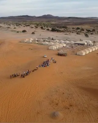 a group of people riding horses in the desert at Safari trips Morocco luxury camp in Merzouga