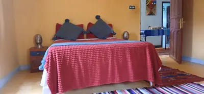 a bedroom with a bed with a red blanket at Moha House in Merzouga