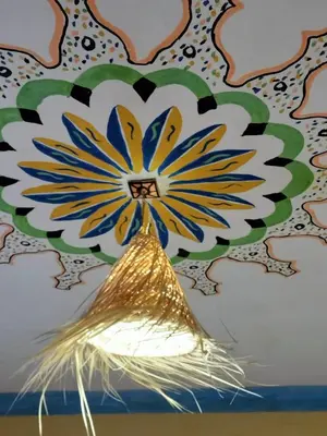 a vase with a yellow and blue flower on a wall at Moha House in Merzouga
