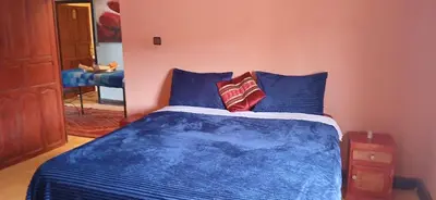 a bedroom with a blue bed with blue pillows at Moha House in Merzouga