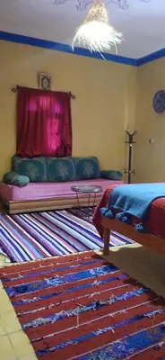 a bedroom with a bed with a curtain and a rug at Moha House in Merzouga