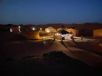 a group of people standing in a desert at night at Camp Sahara Feeling in El Gouera