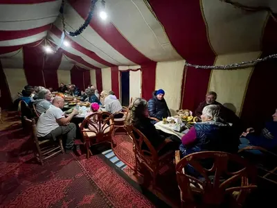 a group of people sitting at tables in a tent at Camp Sahara Feeling in El Gouera