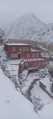 a large red brick building with snow on the ground at Gite D'etape Ait Ali Nito Assounfou in Megdaz